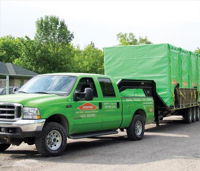 A SERVPRO truck and trailer pulling up to a house