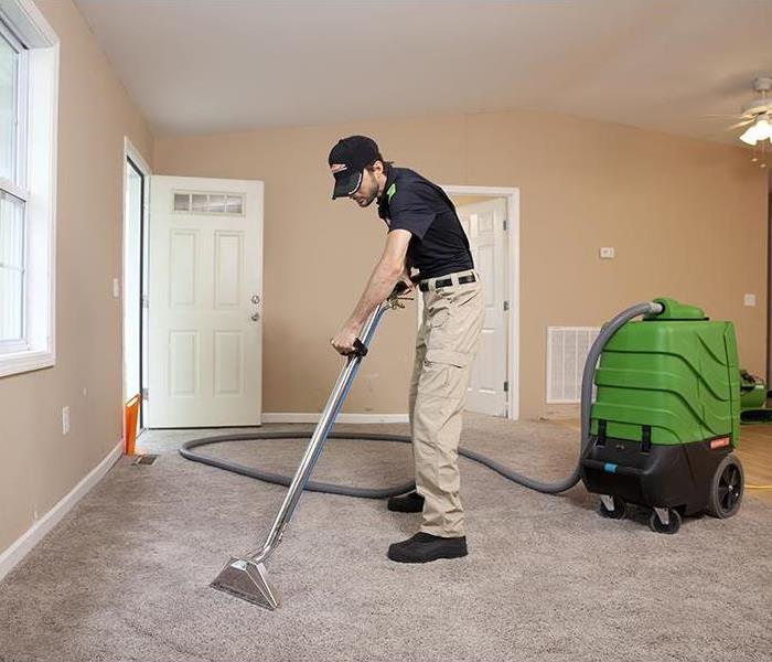 A SERVPRO employee using an extractor to pull water out of a wet carpet